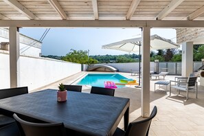 Ett takförsett utomhusområde med en pool, sittplatser och utsikt över landskapet.