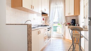 Eine Küche mit weißen Schränken, einer Arbeitsplatte aus Granit, einer Spüle und einem Barhocker.