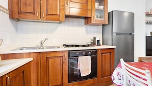 Een keuken met houten kastjes, een roestvrijstalen koelkast en een betegelde achterwand.