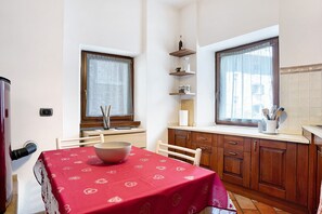 Eine Küche mit Holzschränken, einem Tisch mit roter Tischdecke und einem Fenster mit Vorhängen.