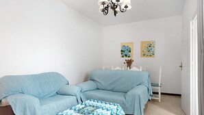 Ein Zimmer mit einer Sofagarnitur, einem kleinen Tisch und zwei an der Wand befestigten Bildern.