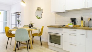 A modern kitchen with white cabinets, a built-in oven, and a wooden countertop. There is a dining table with yellow chairs and a vase with flowers. - Nice Apartment with Pool (Torrevieja)