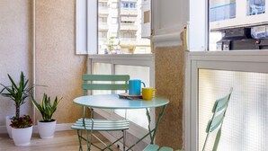 A balcony with a small table, two chairs, and potted plants. - Nice Apartment with Pool (Torrevieja)