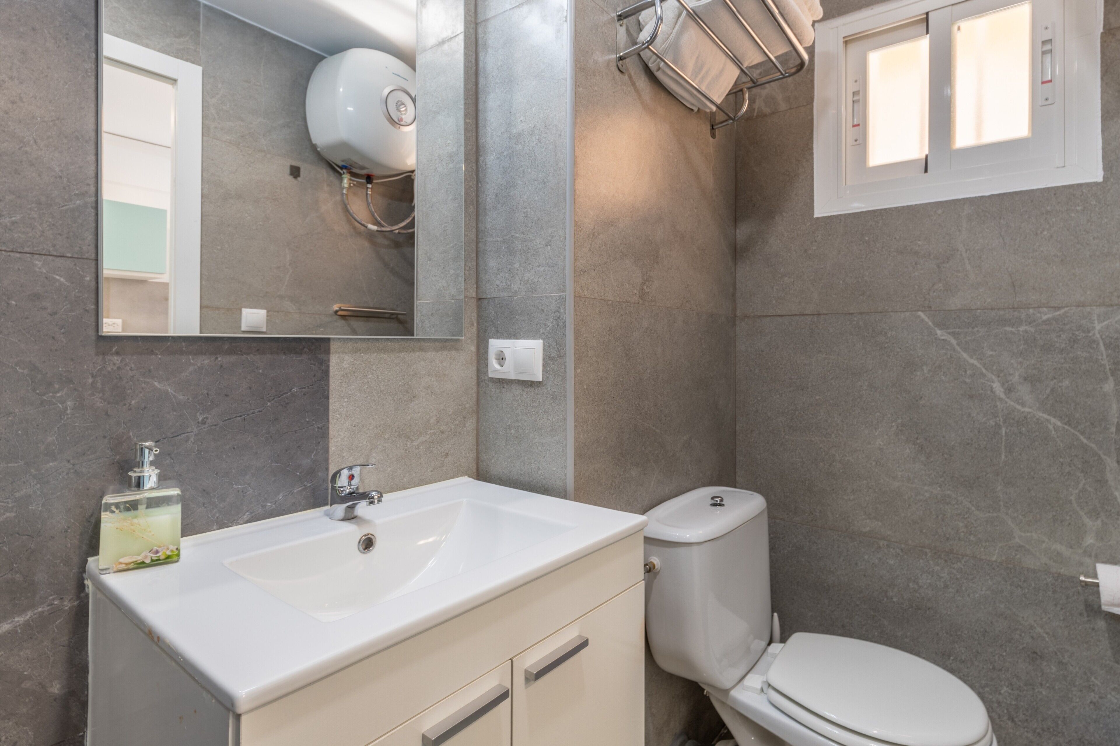Un baño moderno con un lavabo, espejo y retrete blancos.