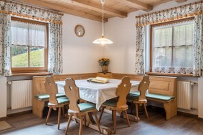 Un espace repas avec une table ronde, des chaises en bois et un luminaire suspendu.