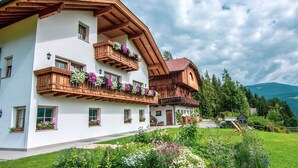 Ein traditionelles Chalet mit mehreren Balkonen, Blumenkästen und einem gepflegten Garten.
