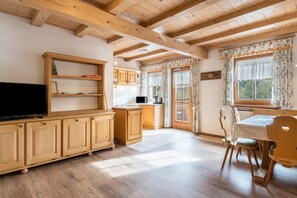 Un intérieur en bois comprenant un téléviseur, des placards, une table à manger, des chaises et un coin cuisine.