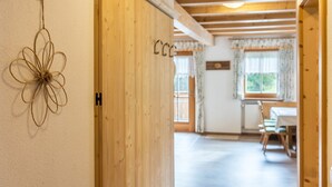 Ein Holzinterieur mit einer Tür, die mit 'H' gekennzeichnet ist, einer Blumendekoration und einem Essbereich mit Tisch und Stühlen.