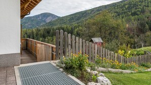 Ein Holzbalkon mit Blick auf einen bewaldeten Berg.