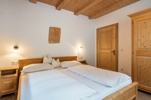 Une chambre à coucher avec un lit en bois, deux tables de chevet, une armoire en bois et un luminaire fixé au mur.