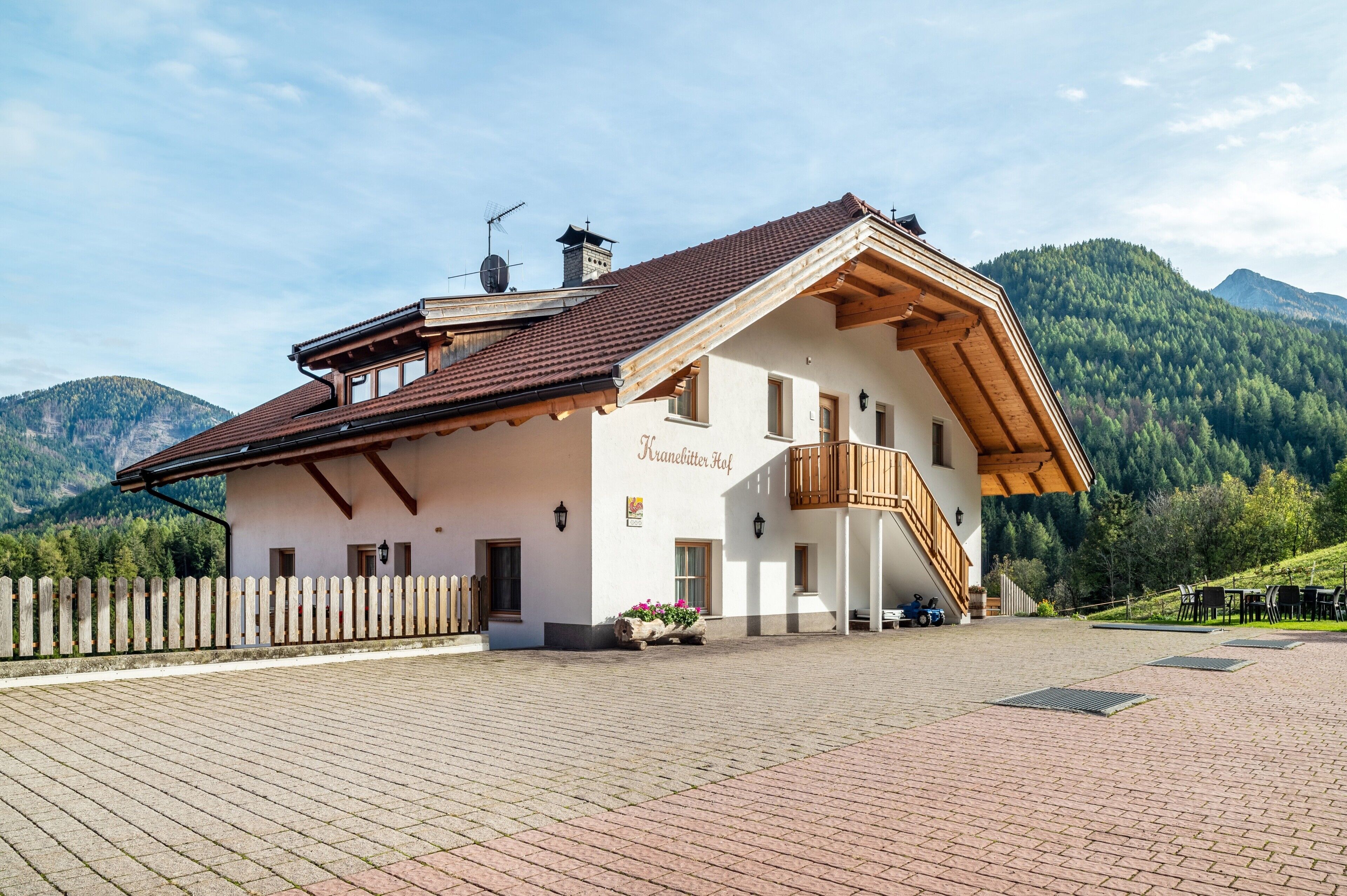 Un edificio de estilo alpino tradicional con techo inclinado, balcón de madera y un patio empedrado.