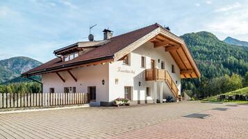 Un edificio de estilo alpino tradicional con techo inclinado, balcón de madera y un patio empedrado.