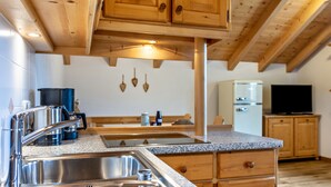 Eine Küche mit Holzausstattung, einer Granitarbeitsplatte, einer Spüle aus Edelstahl und einem Kühlschrank.