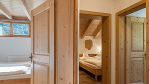 A wooden door leading to a bedroom with a bed, a window, and a wall-mounted decoration. - Apartment 'Kranebitterhof Alpenrose' with Mountain View, Shared Garden and Wi-Fi (Valdaora)