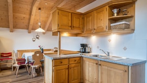 A kitchen with wooden cabinets, a granite countertop, a coffee maker, and a sink. - Apartment 'Kranebitterhof Alpenrose' with Mountain View, Shared Garden and Wi-Fi (Valdaora)