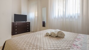Una habitación de hotel con cama, cómoda, televisor de pantalla plana y espejo.