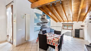 A dining area with a wooden ceiling, a stone wall art piece, and a tiled floor. - Apartment 'Verona' with Shared Garden, Wi-Fi and Air Conditioning (VERONA)