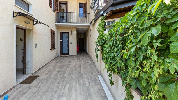 A narrow alleyway with a wooden floor, a building with a balcony, and a wall covered in green ivy. - Apartment 'Verona' with Shared Garden, Wi-Fi and Air Conditioning (VERONA)