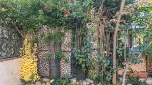 A garden with a variety of plants, a stone wall, and a wooden fence. - Apartment 'Verona' with Shared Garden, Wi-Fi and Air Conditioning (VERONA)