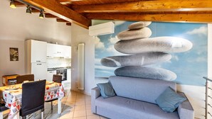 A living room with a sofa, dining table, chairs, kitchen area, and a wall mural. - Apartment 'Verona' with Shared Garden, Wi-Fi and Air Conditioning (VERONA)