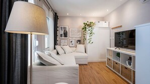 Una sala de estar moderna con un sofá, un televisor, una lámpara y cuadros en la pared.