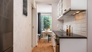 Una cocina estrecha con armarios blancos, encimera de madera y vistas a la vegetación exterior.