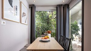 Un comedor con una mesa, sillas, un cuenco de fruta y un florero con flores secas.