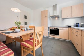 Une cuisine moderne avec des meubles en bois, une table à manger avec des chaises et un four encastré.