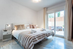 Un dormitorio con cama, mesita de noche y vistas al exterior.