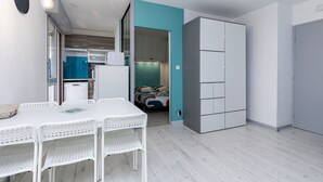 Ein kompakter Raum mit einer Küchenzeile, einer Essecke mit Tisch und Stühlen sowie einem Kleiderschrank.