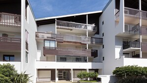 Ein mehrstöckiges Wohngebäude mit Balkonen, einer Garage und blauem Himmel.