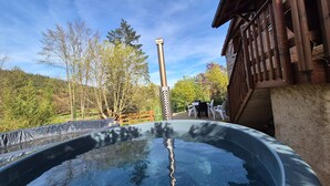 A hot tub with a wooden deck, surrounded by trees and a wooden fence. - Le Chalet Cosy - Label Valeurs Parc Naturel Régional (Weiterswiller)