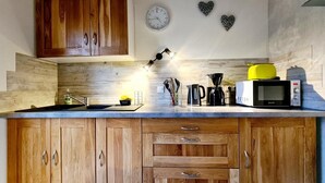 Una cocina con armarios de madera, microondas, cafetera y un reloj en la pared.