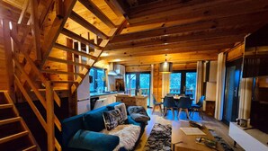 Een houten chalet inrichting met een trap, een bank, een eettafel en een keukenhoek.