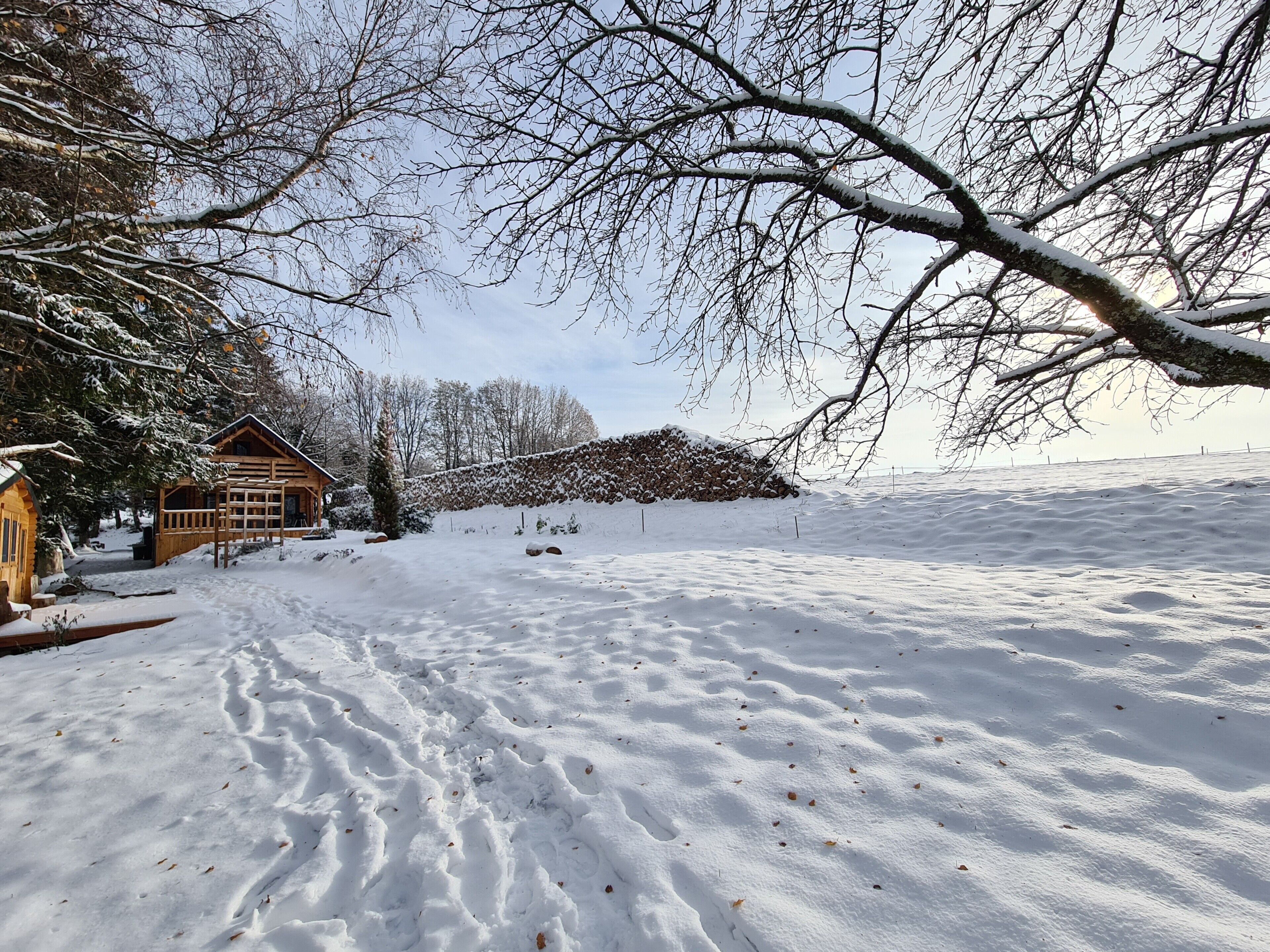 A snow-covered landscape with a wooden cabin and a stone wall.