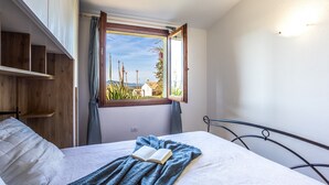 A bedroom with a bed, a window, and a view of the outside. - Holiday Home 'Casa Gio' with Sea View, Garden, Shared Pool and Wi-Fi (Badesi)