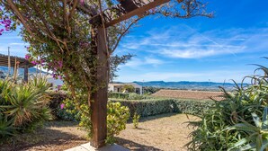 A garden with a pergola, various plants, and a view of distant buildings. - Holiday Home 'Casa Gio' with Sea View, Garden, Shared Pool and Wi-Fi (Badesi)