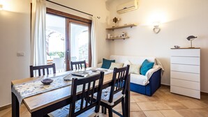 A dining area with a table, chairs, and a sofa. - Holiday Home 'Casa Gio' with Sea View, Garden, Shared Pool and Wi-Fi (Badesi)