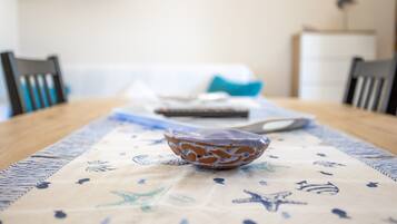 Una mesa de comedor con un mantel estampado, un cuenco decorativo y un control remoto.