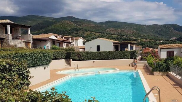 A swimming pool with a mountain backdrop, surrounded by buildings. - Holiday Home 'Casa Gio' with Sea View, Garden, Shared Pool and Wi-Fi (Badesi)