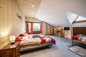 Un dormitorio con cama, escritorio, silla, televisor y ventana.