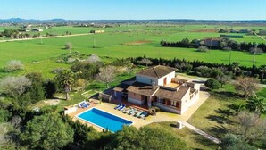 Una casa con piscina, rodeada de campos verdes y árboles.