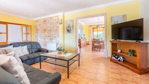 Una sala de estar con sofá, mesa de centro, mueble para televisión y pared de ladrillo.