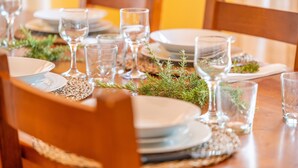 Una mesa de comedor preparada con platos, vasos y follaje.