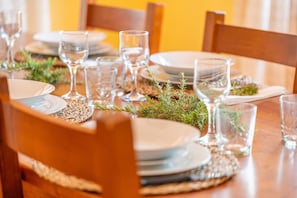 A dining table set with plates, glasses, and a centerpiece of greenery.