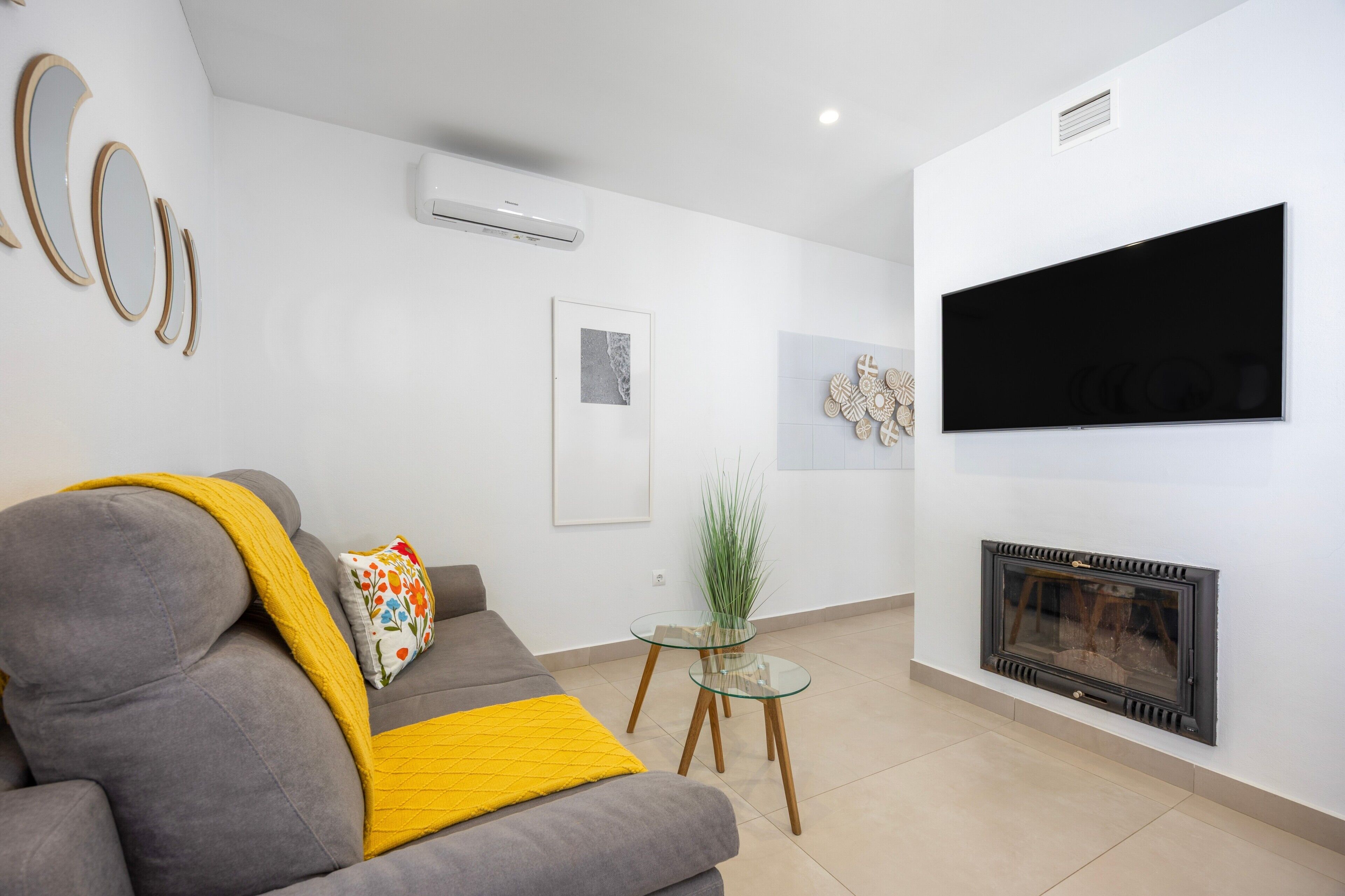A living room with a sofa, a fireplace, a TV, and a small table with a plant.