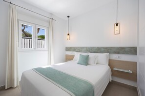 A bedroom with a bed, a window with curtains, a headboard, and two pendant lights. - Casita Meraki 2 with Heated Indoor Pool, Garden, Terrace and Wi-Fi (Chiclana de la Frontera)