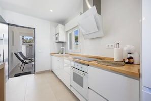 A modern kitchen with white cabinets, a wooden countertop, and a built-in oven. - Casita Meraki 2 with Heated Indoor Pool, Garden, Terrace and Wi-Fi (Chiclana de la Frontera)