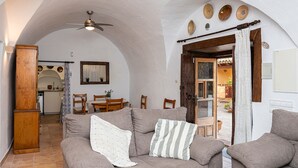 Ein gemütliches Wohnzimmer mit Sofa, Sesseln, einem Esstisch und einer Küchenzeile.