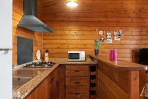 Une cuisine avec des murs en bois, un four à micro-ondes, un évier et une cuisinière à gaz.